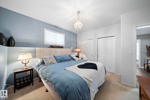 Carpeted bedroom featuring multiple closets and hanging lights - 103 Adams Close, Red Deer, AB - Indoor Photo Showing Bedroom