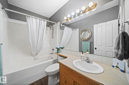 Bathroom featuring vanity, shower / tub combo with curtain, and dark wood finished floors - 103 Adams Close, Red Deer, AB - Indoor Photo Showing Bathroom