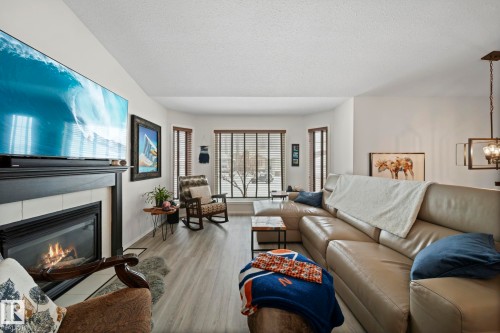 Living area featuring a tile fireplace, wood finished floors, and a textured ceiling - 103 Adams Close, Red Deer, AB - Indoor Photo Showing Living Room With Fireplace