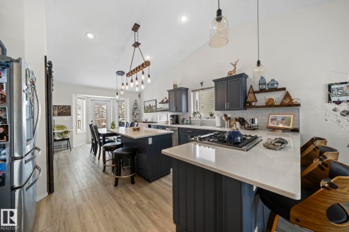 Kitchen featuring a breakfast bar area, a peninsula, stainless steel appliances, a kitchen island, and open shelves - 103 Adams Close, Red Deer, AB - Indoor Photo Showing Kitchen With Upgraded Kitchen