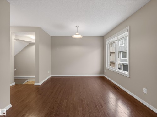 Unfurnished dining area featuring dark wood-style flooring and a textured ceiling - 125 655 Tamarack Road, Edmonton, AB - Indoor Photo Showing Other Room