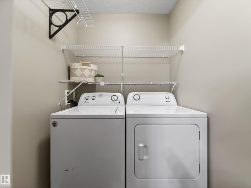 Laundry room featuring a textured ceiling and washing machine and clothes dryer - 125 655 Tamarack Road, Edmonton, AB - Indoor Photo Showing Laundry Room