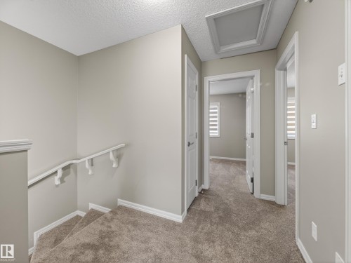 Hallway with carpet flooring, a textured ceiling, and an upstairs landing - 125 655 Tamarack Road, Edmonton, AB - Indoor Photo Showing Other Room