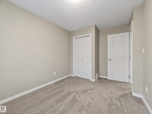 Unfurnished bedroom with carpet floors, a closet, and a textured ceiling - 125 655 Tamarack Road, Edmonton, AB - Indoor Photo Showing Other Room