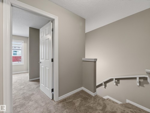 Hallway with light colored carpet, a textured ceiling, and an upstairs landing - 125 655 Tamarack Road, Edmonton, AB - Indoor Photo Showing Other Room
