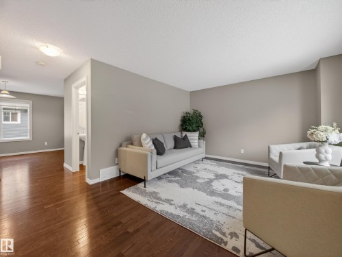 Living area featuring dark wood-type flooring and a textured ceiling - 125 655 Tamarack Road, Edmonton, AB - Indoor
