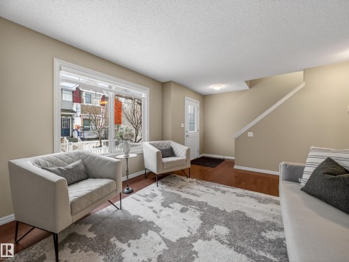Living room featuring wood finished floors and a textured ceiling - 125 655 Tamarack Road, Edmonton, AB - Indoor Photo Showing Living Room