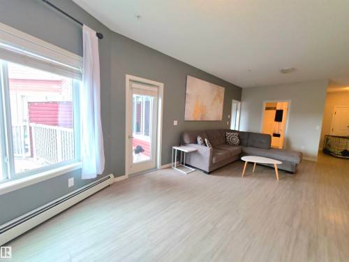 Living room with a baseboard heating unit and light wood-style flooring - 437 1818 Rutherford Road, Edmonton, AB - Indoor