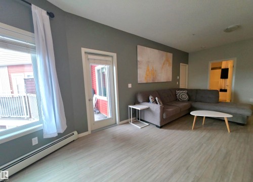 Living area with a baseboard radiator and light wood-style floors - 437 1818 Rutherford Road, Edmonton, AB - Indoor Photo Showing Other Room