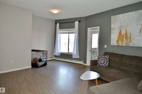 Living area featuring wood finished floors, a textured ceiling, and baseboard heating - 437 1818 Rutherford Road, Edmonton, AB - Indoor Photo Showing Living Room