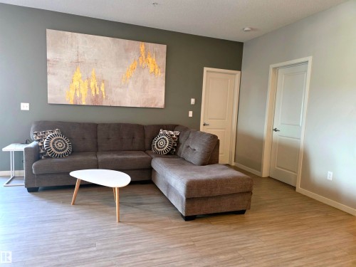 Living room featuring a textured ceiling and light wood-type flooring - 437 1818 Rutherford Road, Edmonton, AB - Indoor Photo Showing Living Room