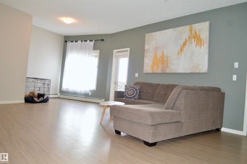 Living room with wood finished floors and baseboard heating - 437 1818 Rutherford Road, Edmonton, AB - Indoor Photo Showing Living Room