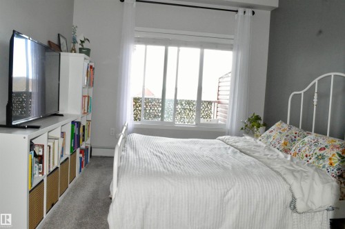 Carpeted bedroom with baseboards and a baseboard heating unit - 437 1818 Rutherford Road, Edmonton, AB - Indoor Photo Showing Bedroom