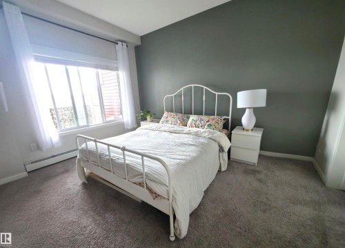 Carpeted bedroom with baseboards and a baseboard heating unit - 437 1818 Rutherford Road, Edmonton, AB - Indoor Photo Showing Bedroom