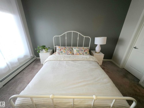 Carpeted bedroom with a baseboard radiator and baseboards - 437 1818 Rutherford Road, Edmonton, AB - Indoor Photo Showing Bedroom