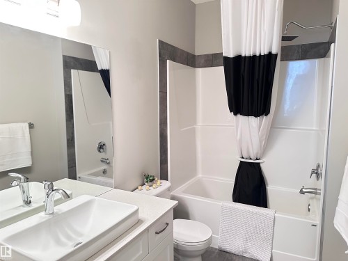 Bathroom featuring a white rectangular vessel sink, white shaker-style vanity with chrome pulls, and a light-colored solid surface countertop - 437 1818 Rutherford Road, Edmonton, AB - Indoor Photo Showing Bathroom