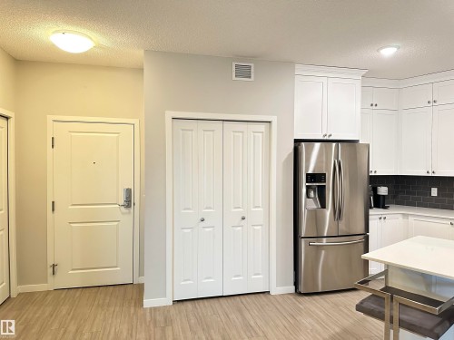 Kitchen and entry area featuring wood-finish flooring - 437 1818 Rutherford Road, Edmonton, AB - Indoor