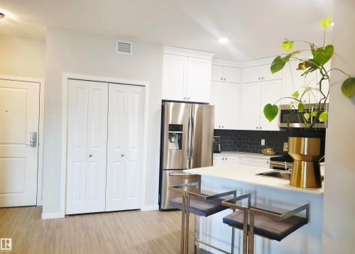 Kitchen featuring stainless steel appliances, a breakfast bar area, white cabinets, light wood-style floors, and recessed lighting - 437 1818 Rutherford Road, Edmonton, AB - Indoor Photo Showing Kitchen