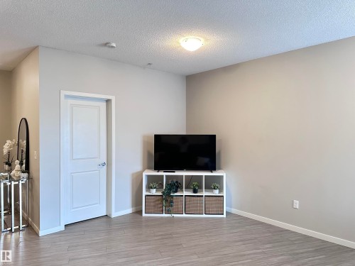 Spacious room with light-toned walls, wood-finish flooring, and white trim - 437 1818 Rutherford Road, Edmonton, AB - Indoor