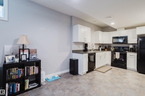 Kitchen featuring black appliances, stone finish flooring, white cabinets, and dark countertops - 326 West Haven Drive, Leduc, AB - Indoor Photo Showing Kitchen
