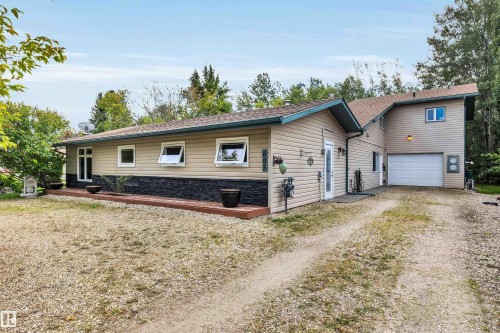 View of front of property featuring driveway, a deck, stone siding, an attached garage, and roof with shingles - 605 6St. Ross Haven, Rural Lac Ste. Anne County, AB - Outdoor
