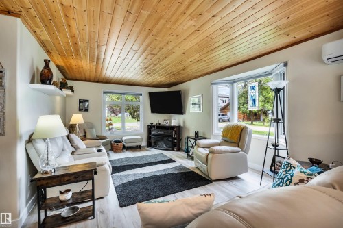 Living area featuring wood ceiling, wood finished floors, and a glass covered fireplace - 605 6St. Ross Haven, Rural Lac Ste. Anne County, AB - Indoor Photo Showing Living Room With Fireplace