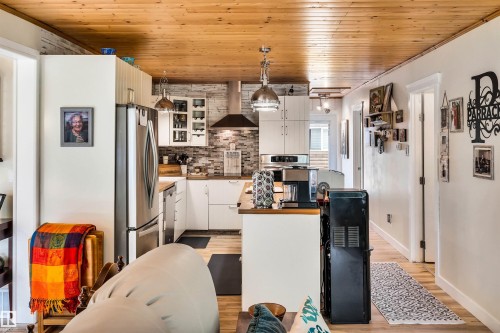 Kitchen with white cabinetry, wooden ceiling, glass insert cabinets, stainless steel appliances, and decorative light fixtures - 605 6St. Ross Haven, Rural Lac Ste. Anne County, AB - Indoor Photo Showing Kitchen
