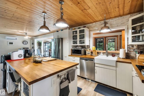 Kitchen featuring white cabinetry, glass fronted cabinets, backsplash, pendant lighting, and wood ceiling - 605 6St. Ross Haven, Rural Lac Ste. Anne County, AB - Indoor Photo Showing Kitchen