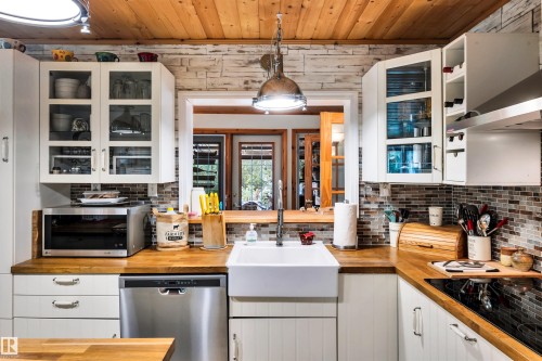 Kitchen featuring glass fronted cabinets, white cabinets, butcher block countertops, stainless steel appliances, and ventilation hood - 605 6St. Ross Haven, Rural Lac Ste. Anne County, AB - Indoor Photo Showing Kitchen