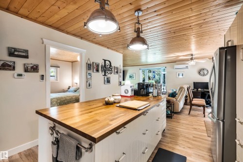Kitchen featuring wood ceiling, butcher block countertops, open floor plan, freestanding refrigerator, and decorative light fixtures - 605 6St. Ross Haven, Rural Lac Ste. Anne County, AB - Indoor