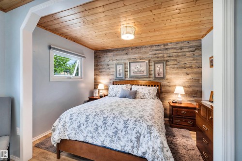 Bedroom with wood ceiling, wooden walls, light wood-style floors, and an accent wall - 605 6St. Ross Haven, Rural Lac Ste. Anne County, AB - Indoor Photo Showing Bedroom