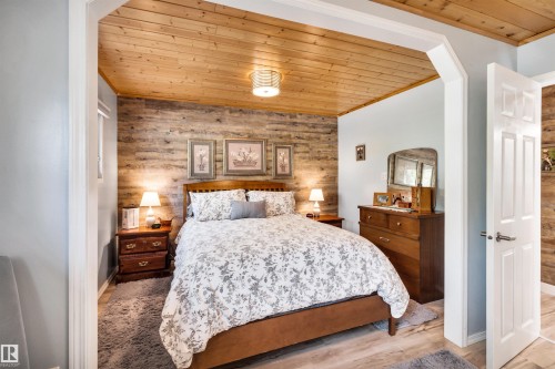 Bedroom featuring wooden ceiling, arched walkways, wood finished floors, an accent wall, and wooden walls - 605 6St. Ross Haven, Rural Lac Ste. Anne County, AB - Indoor Photo Showing Bedroom