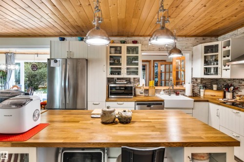 Kitchen with wood counters, pendant lighting, glass fronted cabinets, stainless steel appliances, and wood ceiling - 605 6St. Ross Haven, Rural Lac Ste. Anne County, AB - Indoor Photo Showing Other Room