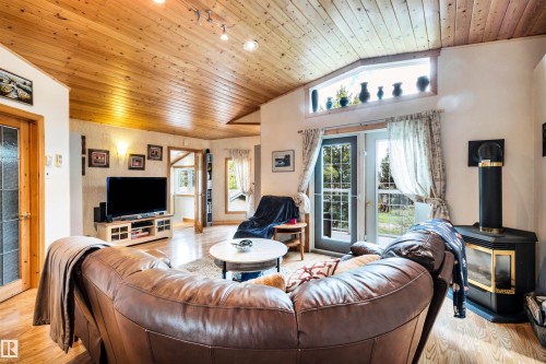 Living room featuring a vaulted wood ceiling, a wood stove, light wood-style flooring, and french doors - 605 6St. Ross Haven, Rural Lac Ste. Anne County, AB - Indoor Photo Showing Living Room