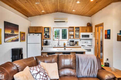 Kitchen featuring white appliances, backsplash, glass fronted cabinets, a center island, and wooden ceiling - 605 6St. Ross Haven, Rural Lac Ste. Anne County, AB - Indoor Photo Showing Kitchen