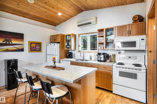 Kitchen featuring white appliances, a center island, a breakfast bar area, wood finish cabinets, and a vaulted wooden ceiling - 605 6St. Ross Haven, Rural Lac Ste. Anne County, AB - Indoor Photo Showing Kitchen With Double Sink