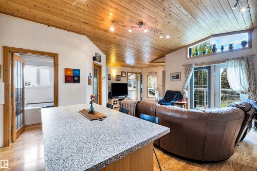 Living room with a vaulted wood ceiling, french doors, light wood finished floors, and plenty of natural light - 605 6St. Ross Haven, Rural Lac Ste. Anne County, AB - Indoor Photo Showing Living Room