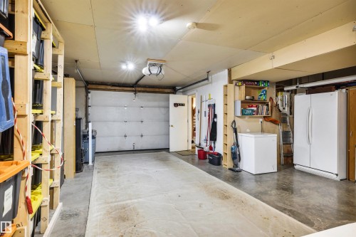 Garage featuring freestanding refrigerator, white refrigerator, and a garage door opener - 605 6St. Ross Haven, Rural Lac Ste. Anne County, AB - Indoor Photo Showing Garage