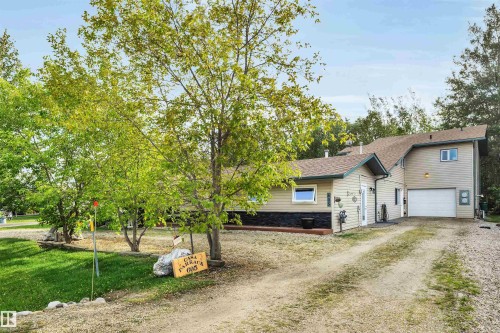 View of front of property featuring dirt driveway, a garage, and a shingled roof - 605 6St. Ross Haven, Rural Lac Ste. Anne County, AB - Outdoor