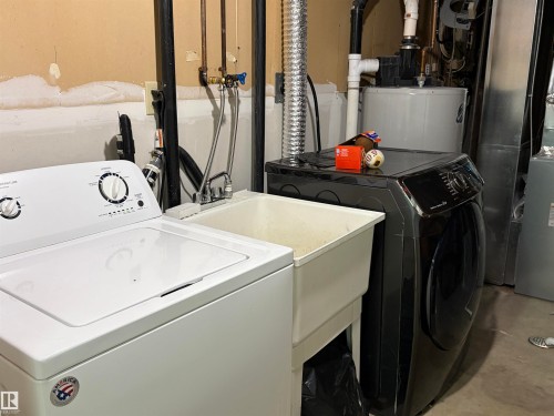 Laundry area with concrete flooring, washer and dryer, and water heater - 2008 4Th Ave, Cold Lake, AB - Indoor Photo Showing Laundry Room
