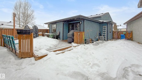 Snow covered back of property with a fenced backyard, a wooden deck, and stucco siding - 7 Chungo Drive, Devon, AB - Outdoor