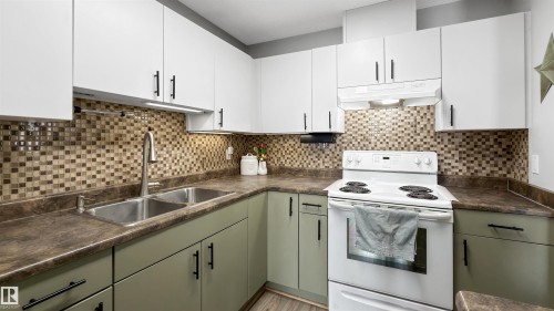 Dual tone kitchen featuring white range with electric stovetop, dark countertops, two tone cabinetry, and tasteful backsplash - 7 Chungo Drive, Devon, AB - Indoor Photo Showing Kitchen With Double Sink