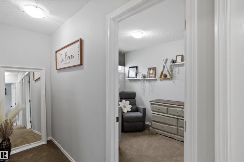 Hallway featuring a textured ceiling and dark carpet - 7 Chungo Drive, Devon, AB - Indoor Photo Showing Other Room