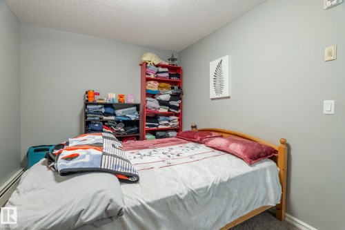 Carpeted bedroom with a textured ceiling and a baseboard heating unit - 207 2203 44 Avenue, Edmonton, AB - Indoor Photo Showing Bedroom