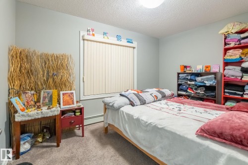 Bedroom with light colored carpet, a textured ceiling, and a baseboard heating unit - 207 2203 44 Avenue, Edmonton, AB - Indoor Photo Showing Bedroom