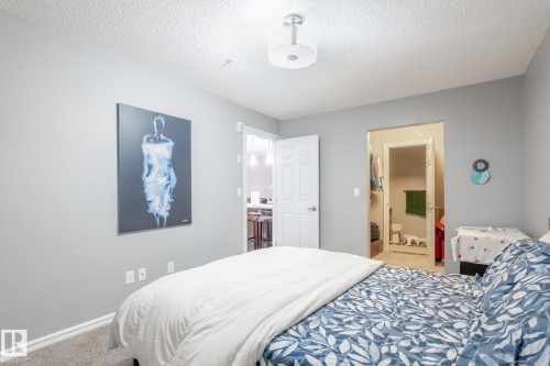 Bedroom with light carpet, a textured ceiling, and connected bathroom - 207 2203 44 Avenue, Edmonton, AB - Indoor Photo Showing Bedroom