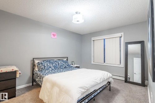 Bedroom featuring light carpet, a textured ceiling, and a baseboard radiator - 207 2203 44 Avenue, Edmonton, AB - Indoor Photo Showing Bedroom