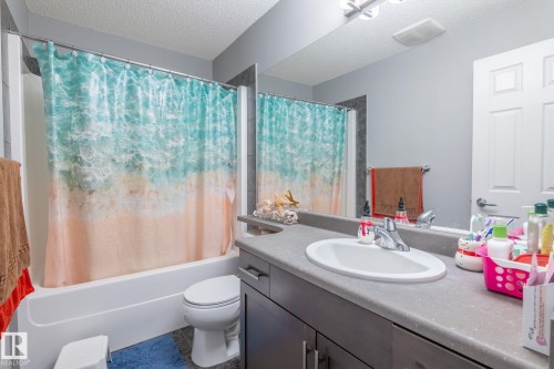 Bathroom featuring vanity, shower / bath combination with curtain, and a textured ceiling - 207 2203 44 Avenue, Edmonton, AB - Indoor Photo Showing Bathroom