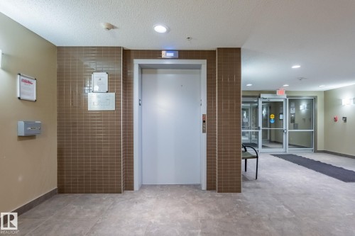 Hall featuring elevator, a textured ceiling, tile walls, and recessed lighting - 207 2203 44 Avenue, Edmonton, AB - Indoor Photo Showing Other Room