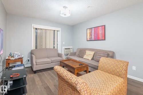 Living room featuring dark wood-style floors and a textured ceiling - 207 2203 44 Avenue, Edmonton, AB - Indoor Photo Showing Living Room